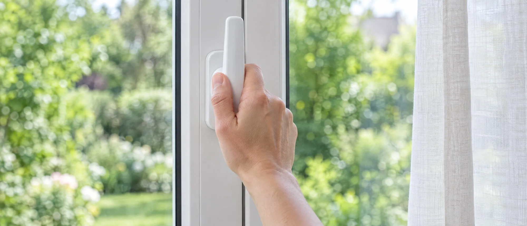 Main sur la poignée d'une fenêtre PVC, tournée vers le haut en position soufflet